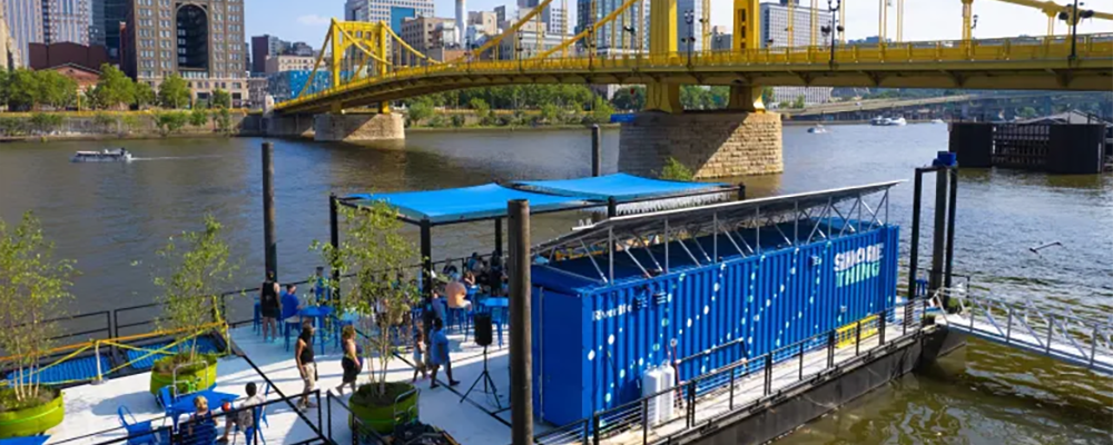 Blue floating restaurant with Pittsburgh in the background